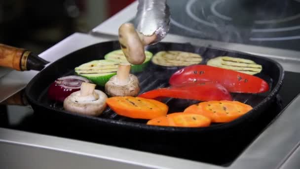 Een chef-kok die in de keuken werkt. Het opwarmen van de champignons en groenten in de pan. Het draaien van de paddestoelen over — Stockvideo