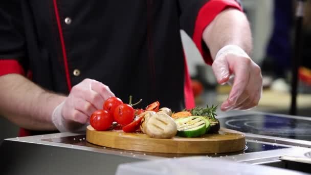 Un chef trabajando en la cocina. Servir verduras fritas en un escritorio de madera — Vídeo de stock