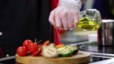 Restoran mutfağı. İki adam yemek servisi yapıyor. Üstüne bir zeytin yağı dökme
