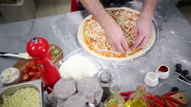 Restoran mutfağı. Pizzanın üstüne peynir koyarak bir şef