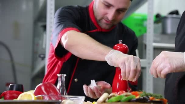 Cocina del restaurante. Dos hombres trabajando en servir platos. Decoración con pimiento rojo — Vídeo de stock