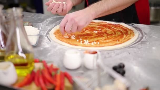 Restaurant keuken. Een chef-kok zetten kaas op de pizza — Stockvideo
