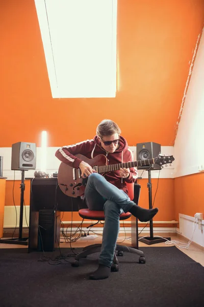Ein Mann mit Brille arbeitet im Atelier. Gitarre spielen — Stockfoto