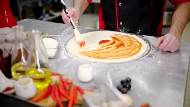 Cocina del restaurante. Un chef pone la pasta de tomate con un cepillo en la masa — Vídeos de Stock