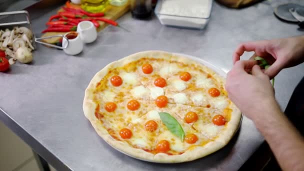 Ресторан кухня. Шеф-повар украшает пиццу зеленью — стоковое видео