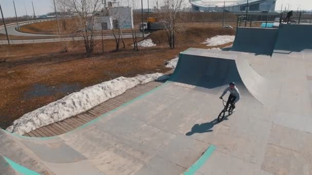 Человек на велосипеде, выполняющий трюки в скейтпарке — стоковое видео