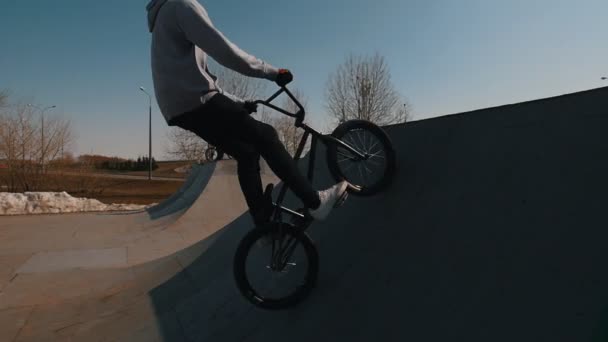 Un hombre talentoso en una bicicleta haciendo un truco en el skatepark — Vídeo de stock