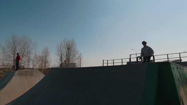 Un hombre en bicicleta haciendo trucos en el skatepark. Salta y sostiene la balanza — Vídeo de stock