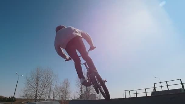Un hombre en bicicleta haciendo trucos en el skatepark. Carreras y mantener un equilibrio en una rueda delantera — Vídeos de Stock