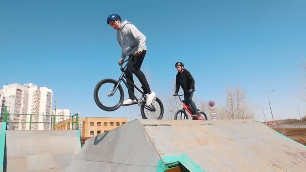 Zwei Männer auf dem Fahrrad im Skatepark bergab — Stockvideo