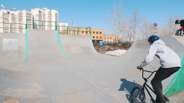 Всадники bmx тренируют свои навыки в скейтпарке. Гонки вверх, выполняя флип и спускаясь — стоковое видео