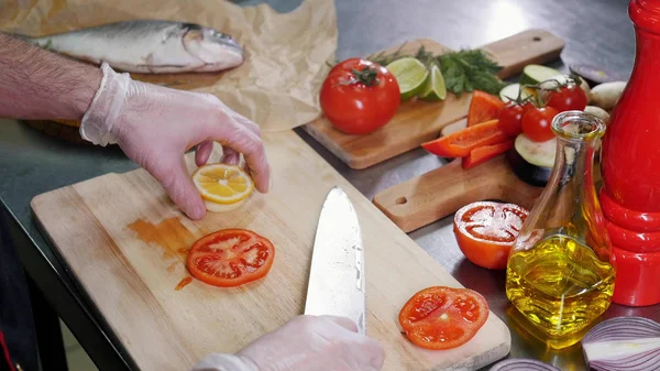 A chef in the kitchen cutting tomato and lemon