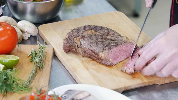 Een chef-kok die in de keuken werkt. Een man snijden de biefstuk op stukken — Stockfoto