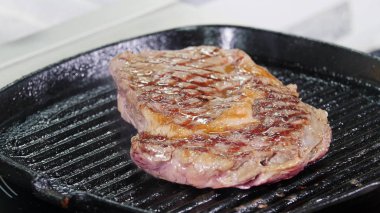 Mutfakta çalışan bir şef. Tavada biftek kızartıyoruz. Et suyu sona eriyor