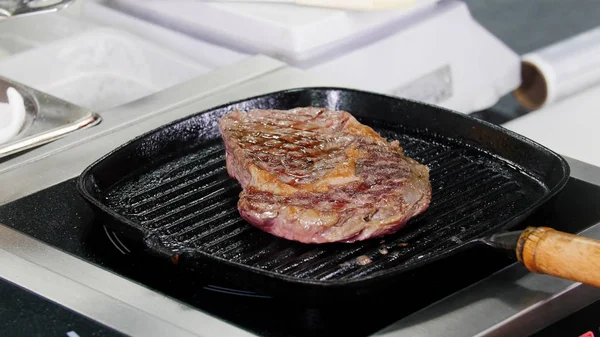 Een chef-kok die in de keuken werkt. Een stukje steak bakken in de pan — Stockfoto