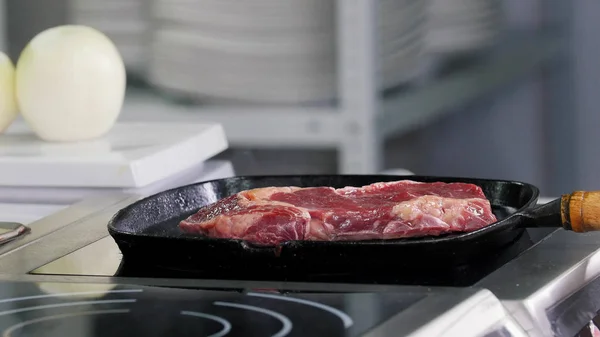 Restaurant keuken. Chef begint met het bakken van een steak in de pan — Stockfoto