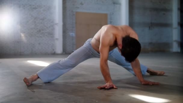 Een atletische man traint zijn stretching. Push-ups maken in een half-split — Stockvideo