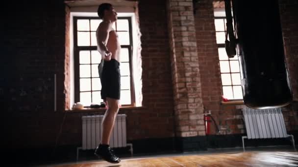 Un athlète sautant par-dessus la corde de saut dans la salle de gym sombre — Video