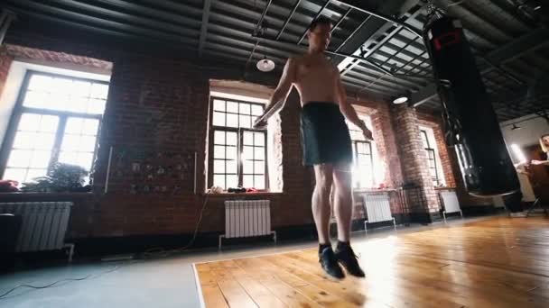 Ein Sportler springt beim Training in der Turnhalle über das Springseil — Stockvideo