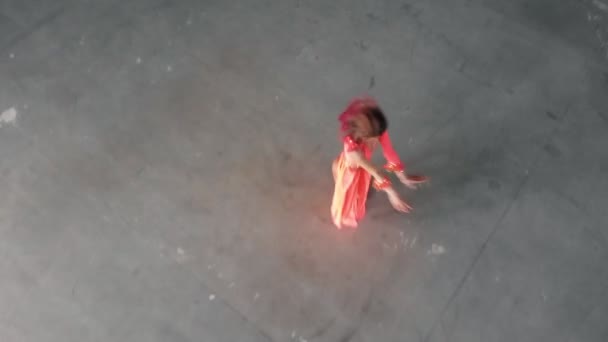 Entrenamiento de ballet en interiores. Mujer joven bailarina en vestido naranja realizando elementos acrobáticos — Vídeos de Stock