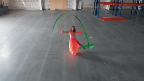 Entrenamiento de ballet en interiores. Mujer joven interpretando elementos de circo con una cinta acrobática — Vídeo de stock