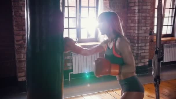 Egy nő bokszoló ütő a lyukasztó táska. Megáll, és mosolyogva — Stock videók