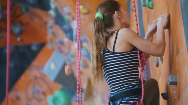 Extreme sport, bouldering. A young woman climbing up on a rock wall. — Stock Video