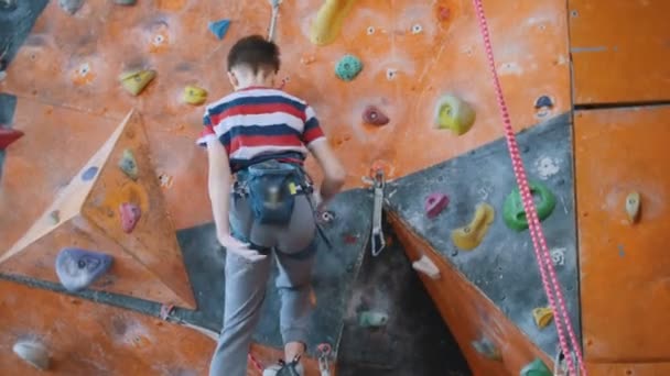 Extreme sport, bouldering. A teenage boy climbing up on a rock wall. — Stock Video