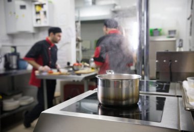Restoran mutfağı. Mutfakta çalışan iki adam. Tabakta kaynayan yiyecekler