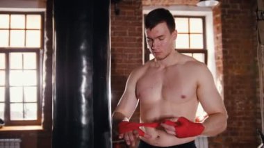 Spor salonunda bir adam antrenmandan önce ellerine bandaj takıyor.