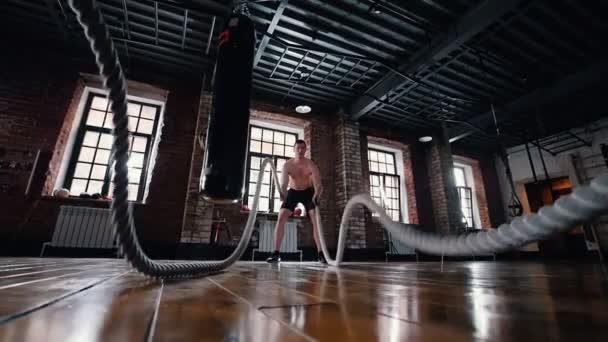 Чоловік на тренуваннях у спортзалі. Навчання рук з мотузками, які б'ються — стокове відео