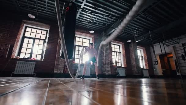 一个在健身房里训练的男人。用绳子打在地板上训练他的手 — 图库视频影像