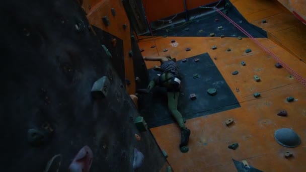 Экстремальный спорт. Молодая женщина спускается со скалистой стены в помещении — стоковое видео