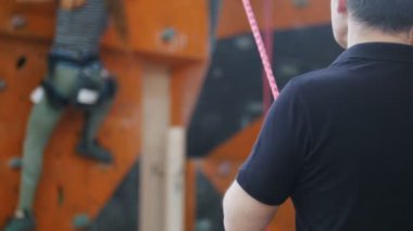 Bouldering' e. Kaya duvarına tırmanan kadını izleyen bir eğitmen.