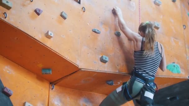 Боулдінг. Молода жінка починає сходження на кам'янисту стіну — стокове відео