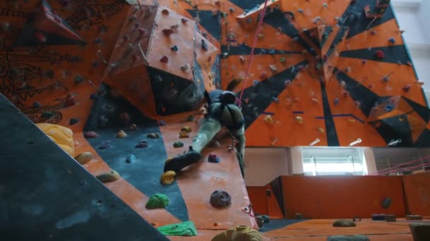 Bouldering. Entertainment Center. En kvinna som klättrar på en stenig vägg — Stockvideo