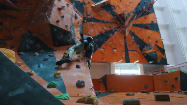 Bouldering. Κέντρο ψυχαγωγίας. Μια γυναίκα ψηλά σε ένα βραχώδες τοίχο — Αρχείο Βίντεο