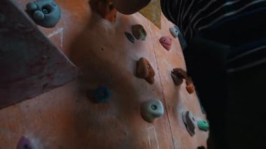 Bouldering' e. Eğlence merkezi. Kayalık bir duvara özenle tırmanan bir kadın.
