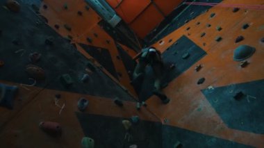 Bouldering' e. Bir çaba ile kayalık bir duvara tırmanma genç bir kadın