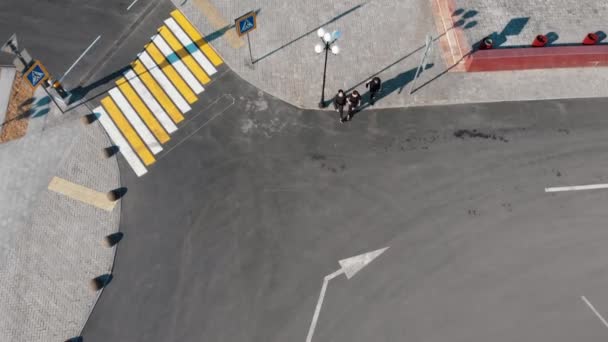 Вид с воздуха на городские улицы. Пешеходный переход. Трое мужчин идут по дороге — стоковое видео