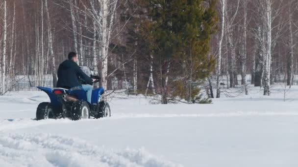 Un hombre con ropa de invierno montando motos de nieve en el bosque — Vídeos de Stock