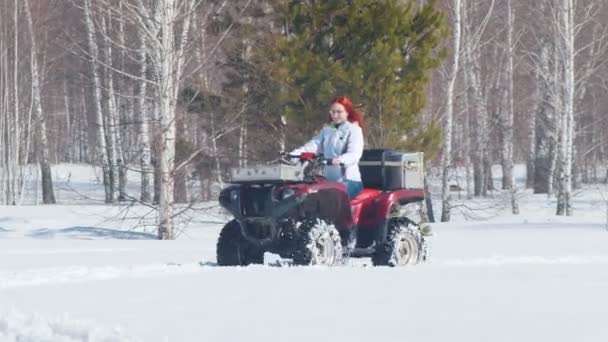 Une forêt d'hiver. Une femme aux cheveux roux chevauchant la motoneige — Video