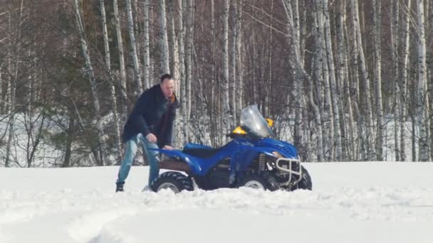 Uma floresta de inverno. Um homem a tirar a mota de neve da corrente de neve — Vídeo de Stock