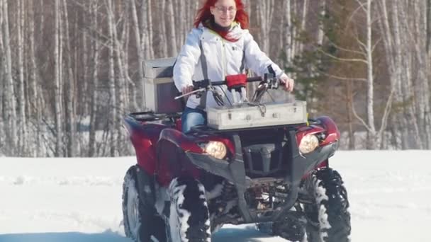 Un bosque de invierno. Una mujer con pelo de jengibre montando una gran moto de nieve — Vídeo de stock