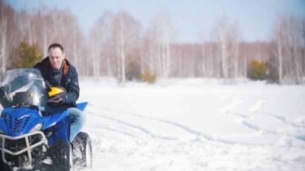 Vinter skog i dagsljus. En man som rider på en stor snöskoter — Stockvideo
