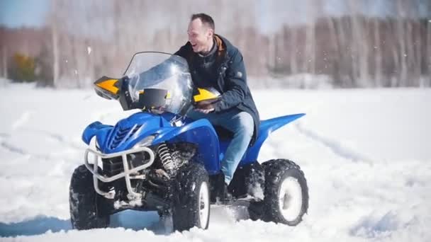 Un bosque de invierno a la luz del día. Un hombre adulto montando una gran moto de nieve azul — Vídeos de Stock