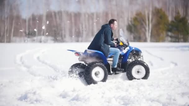 Un bosque de invierno a la luz del día. Un hombre adulto montando una moto de nieve — Vídeos de Stock