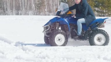 Gün ışığında bir kış ormanı. Soğuk hava. Yetişkin bir adam büyük mavi bir kar arabası sürme
