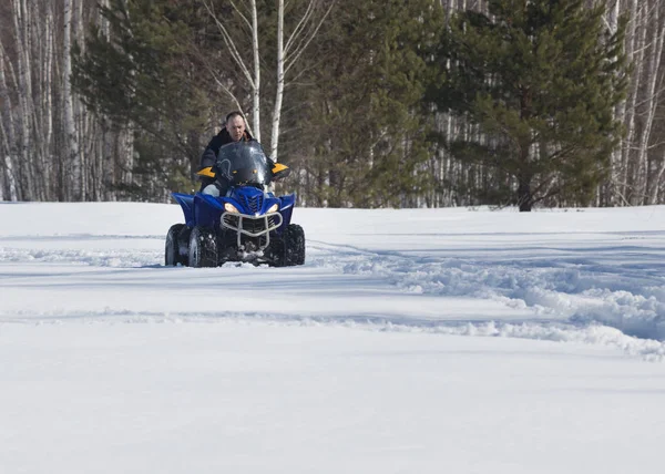 Un hombre con ropa de invierno montando motos de nieve en el bosque — Foto de Stock