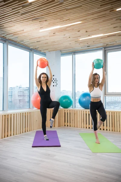 Δύο νέοι Slim γυναίκες κάνουν ασκήσεις κρατώντας μια μπάλα στο στούντιο γυμναστικής — Φωτογραφία Αρχείου